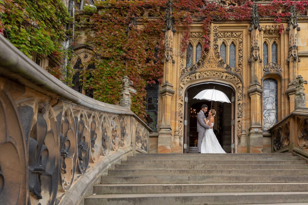 Husband and wife under umbrella outside Carlton Towers