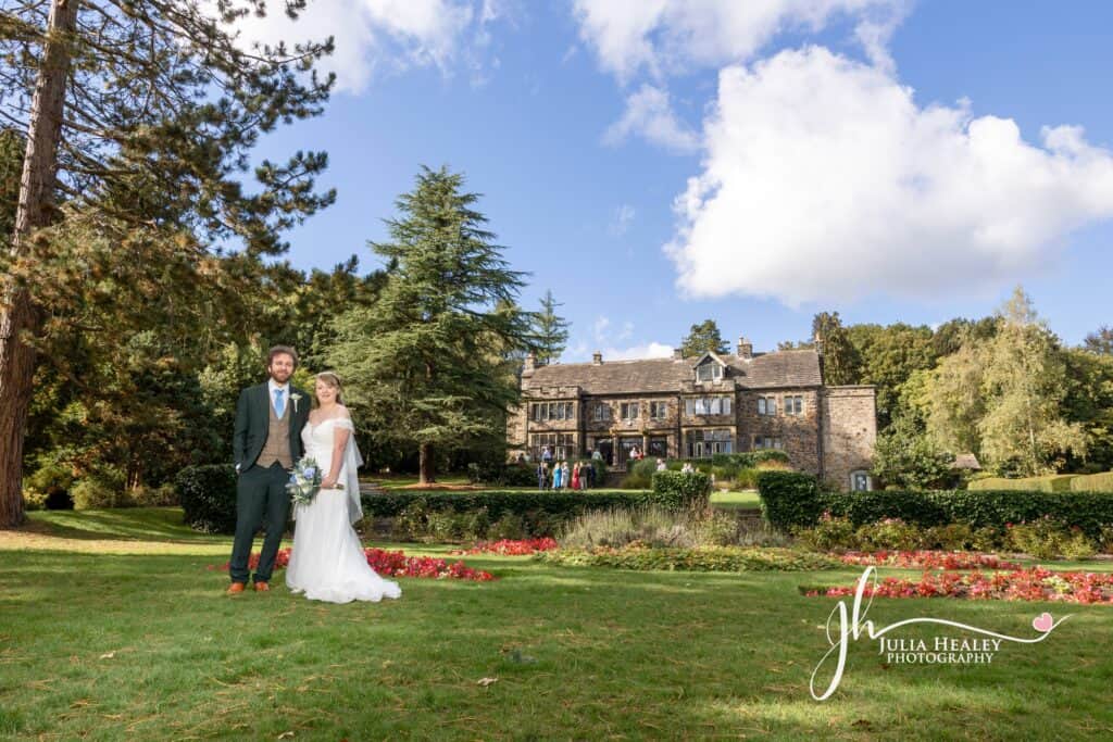 Bride and groom in garden, historic manor background.