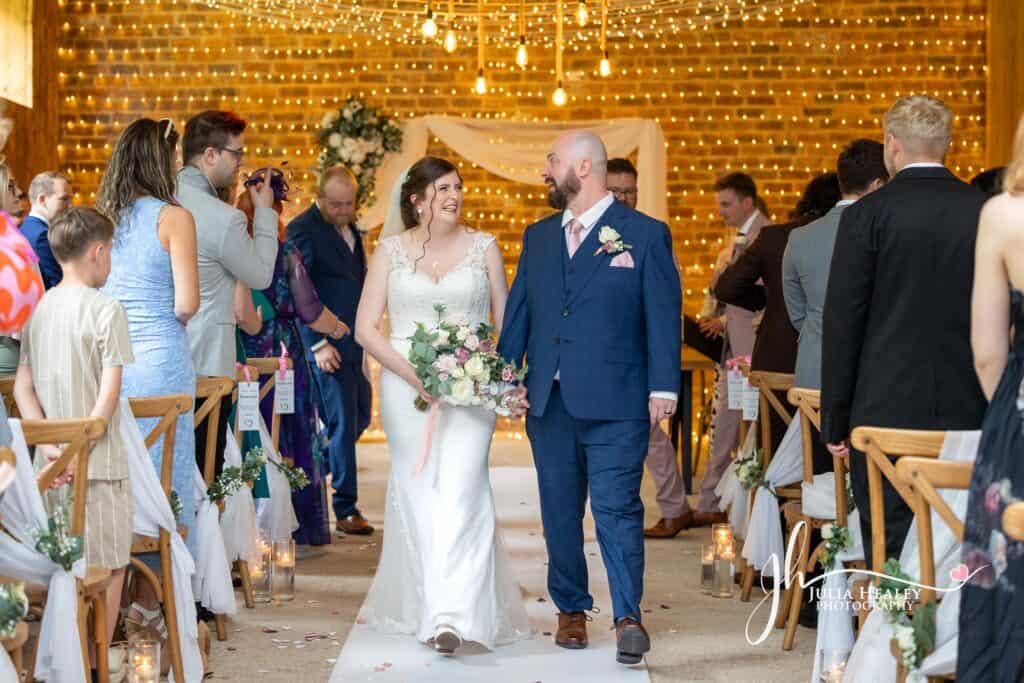 Wedding couple walking down the aisle, smiling happily.