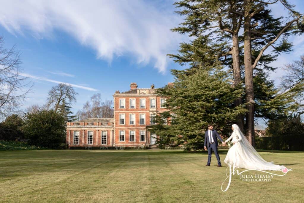 Bride and groom walking outside large brick building.