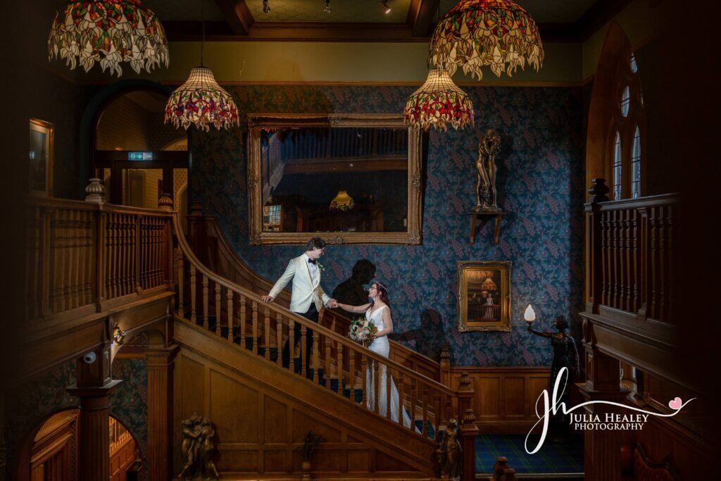 Couple on staircase in elegant historic venue.