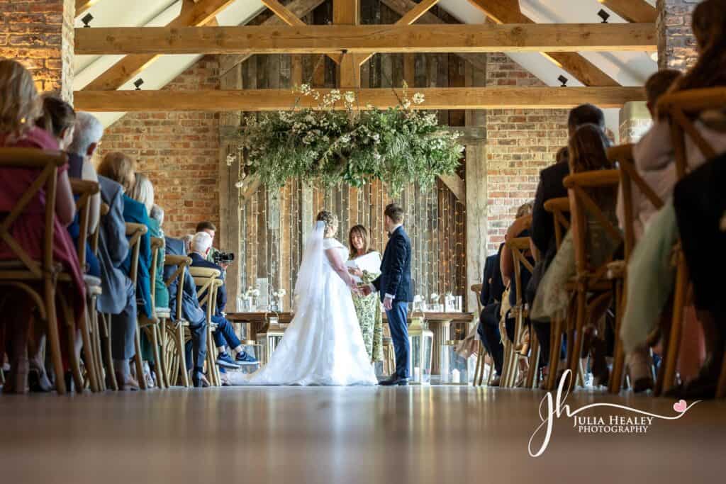 Rustic barn wedding ceremony with guests seated.