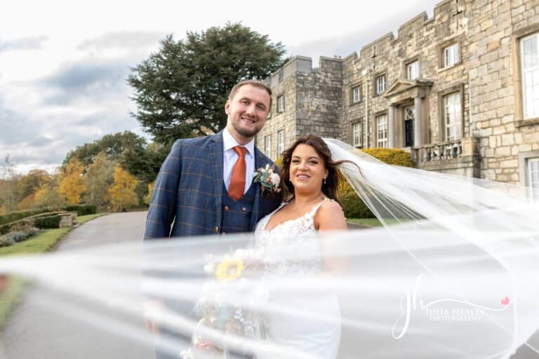 Bride and groom smiling outside a castle.