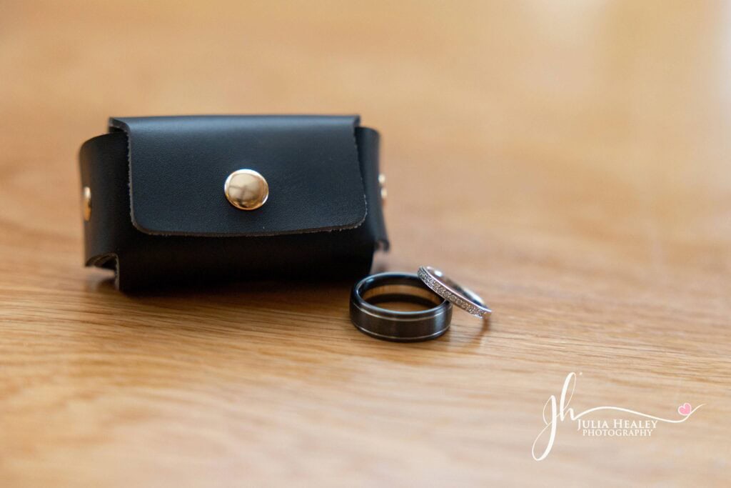 Black leather pouch with silver rings on table.