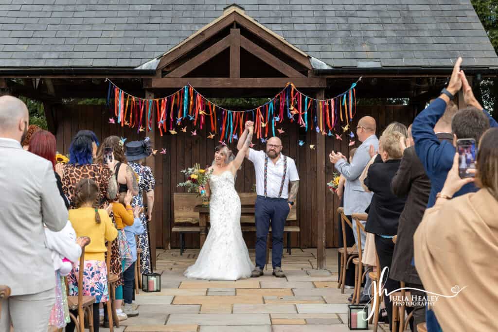 Happy wedding couple celebrated by guests outdoors.